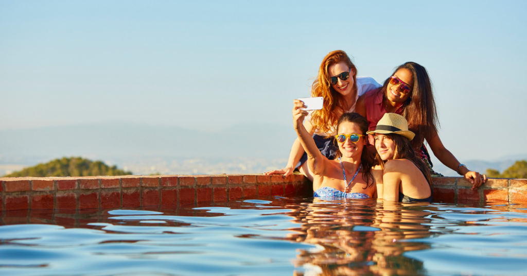 grupo de cuatro chicas jovenes aparecen al fondo de una piscina y se hacen una foto selfie