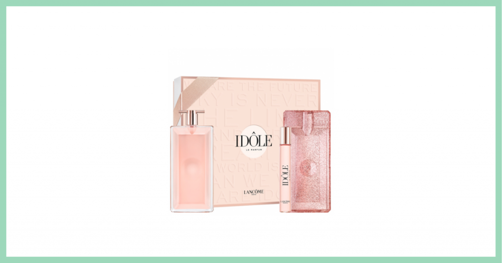 caja rosa con el nombre del perfume que contiene Idole de la marca Lancome junto al frasco de colonia color rosa, un perfume para llevar y una carcasa rosa para proteger perfume