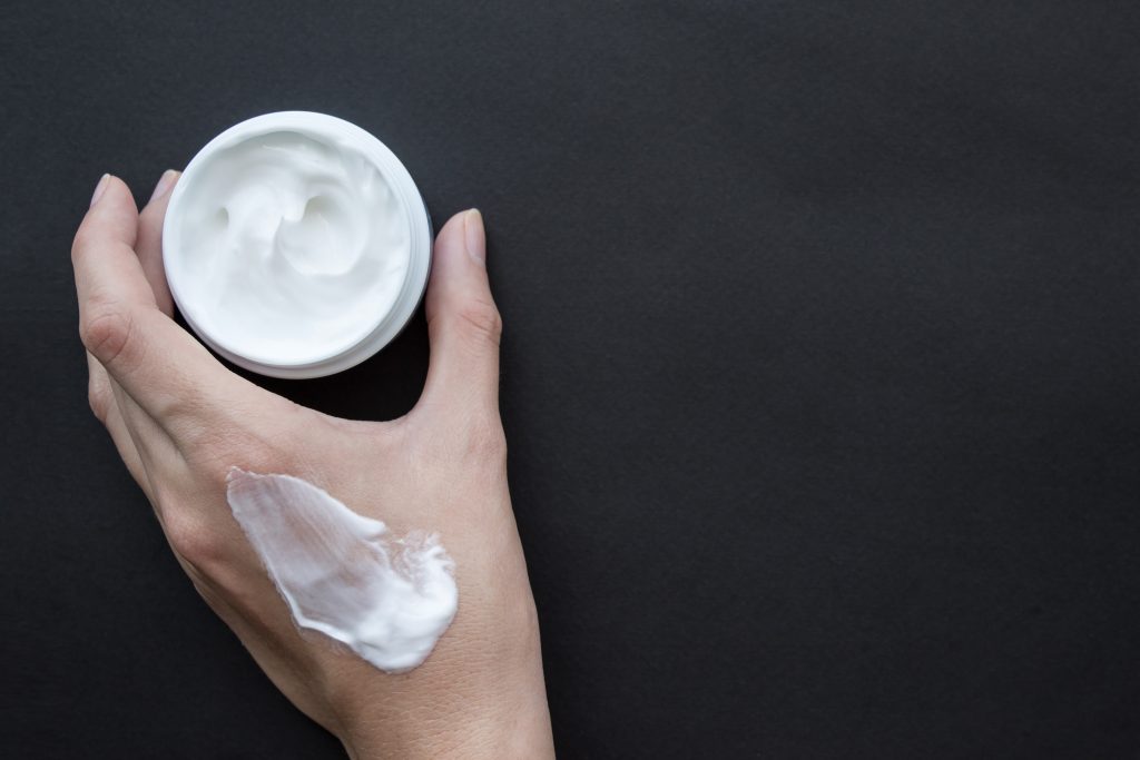 Cream for face or body in female hand. Smear cream on hand
