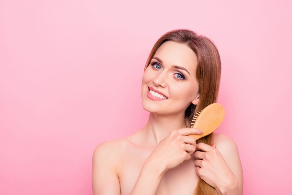 Oil bathroom smooth ideal perfection feminine concept. Close up portrait of pretty attractive satisfied lovely lady with toothy smile using brush for her long soft aromatic hair isolated background