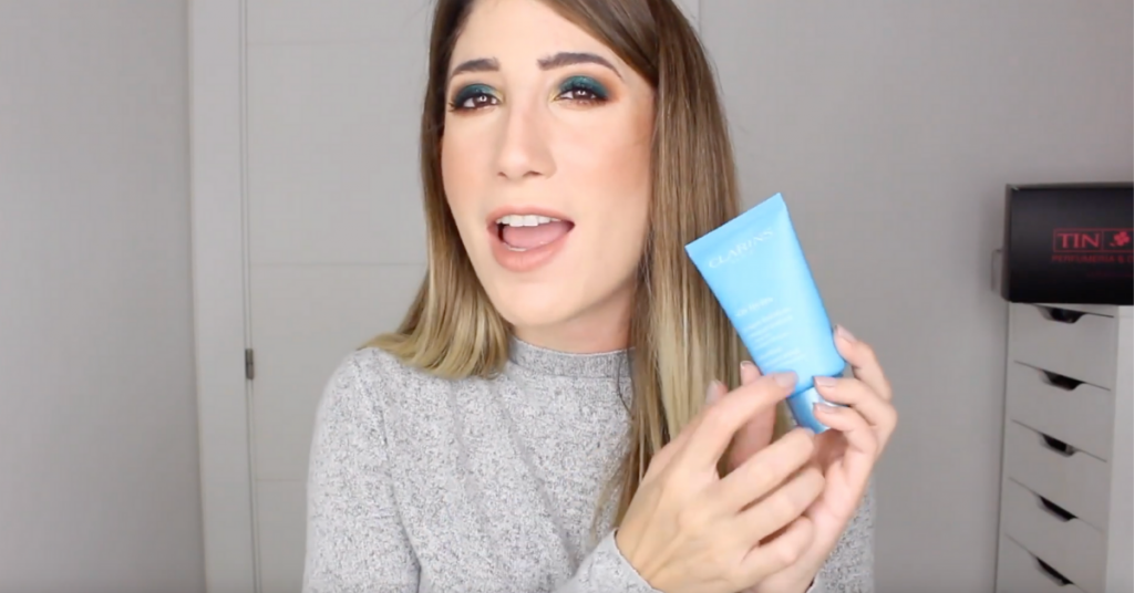 Lucia Castells influencer de tintin enseña una crema azul al fondo se ve la puerta de su habitcion y una estanteria con una caja de perfumerias tin tin
