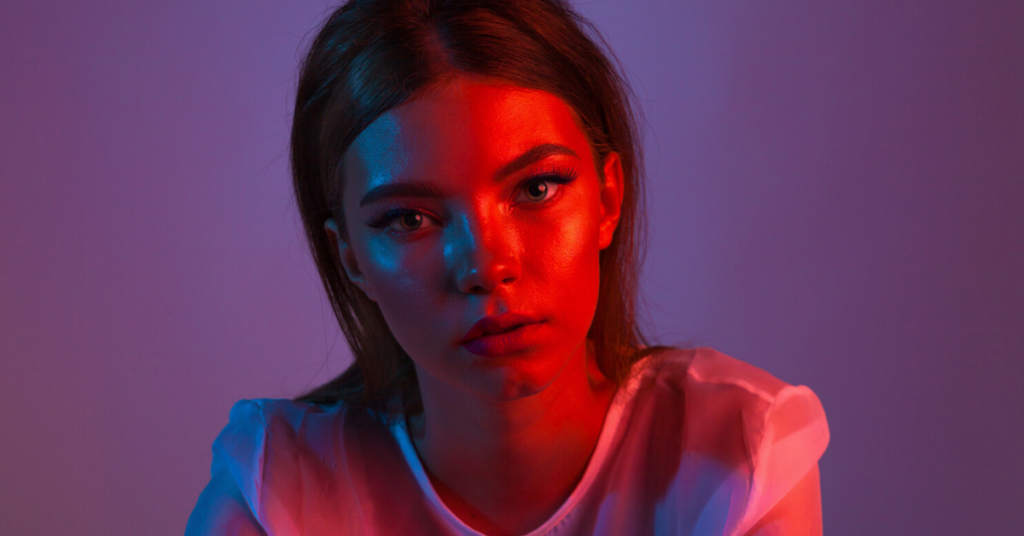 Neon retrato de mujer joven. Foto de estudio Modelo posando en luces moradas, rojas y rosas. La moda se remonta a los años 80 - nuevo concepto de tendencia de los 90.